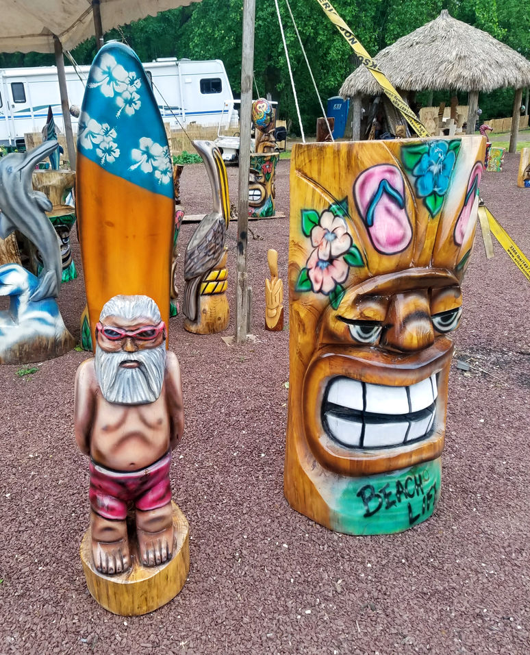 Tiki Murph white pine
chainsaw carving of surfer dude with surfboard and round face tiki with flip flops and "Beach Life".
