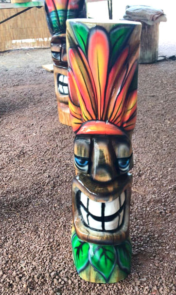 Tiki Murph chainsaw carved white pine small tiki with smiling face and bright floral design with green leaves