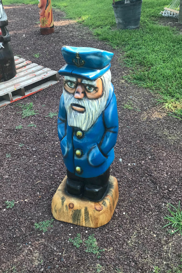 Tiki Murph white pine chainsaw carved small ship captain in blue coat and hat.