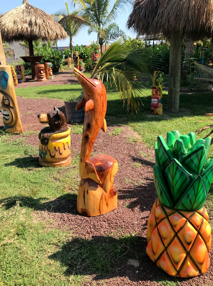 Tiki Murph red cedar chainsaw carved dolphin. A white pine carved pineapple. A white pine bear in a honey pot.