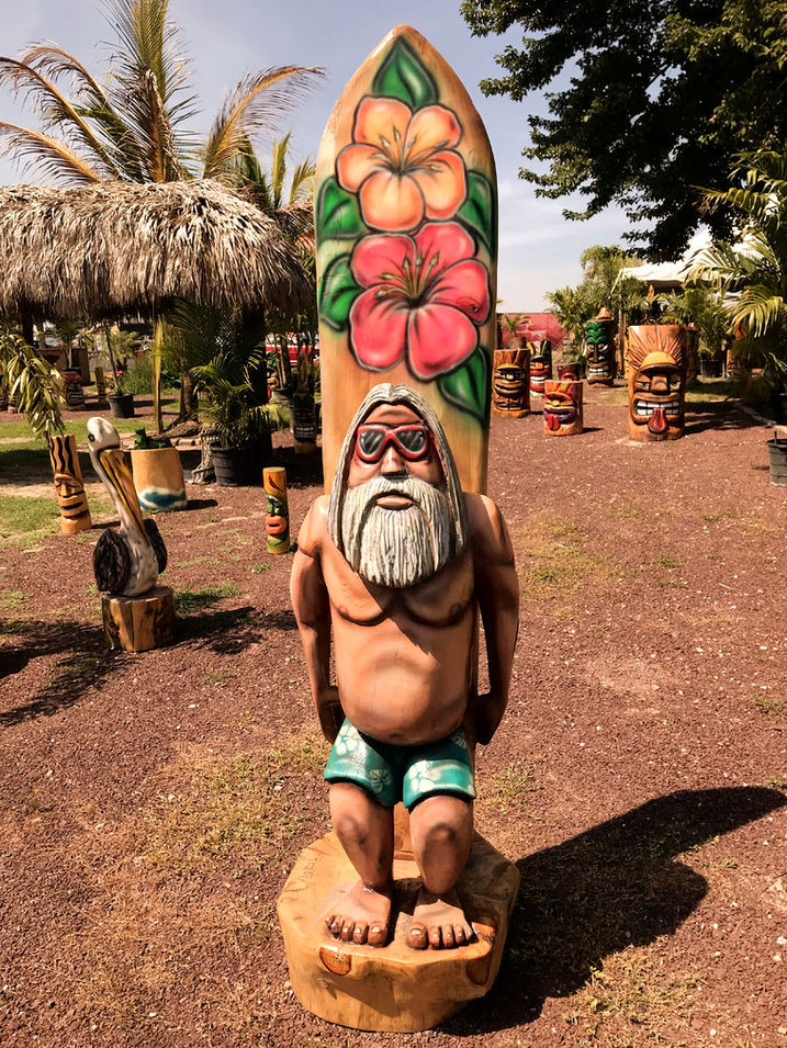 Tiki Murph white pine carved surfer dude with floral surfboard.