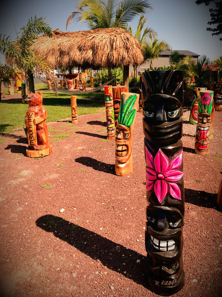 Tiki Murph carved pine double tiki with full body bottom, relief cut pink flower in middle and face top in burnt color.