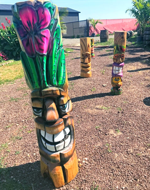 Tiki Murph chainsaw carved white pine tiki with purple flower and green leaves
