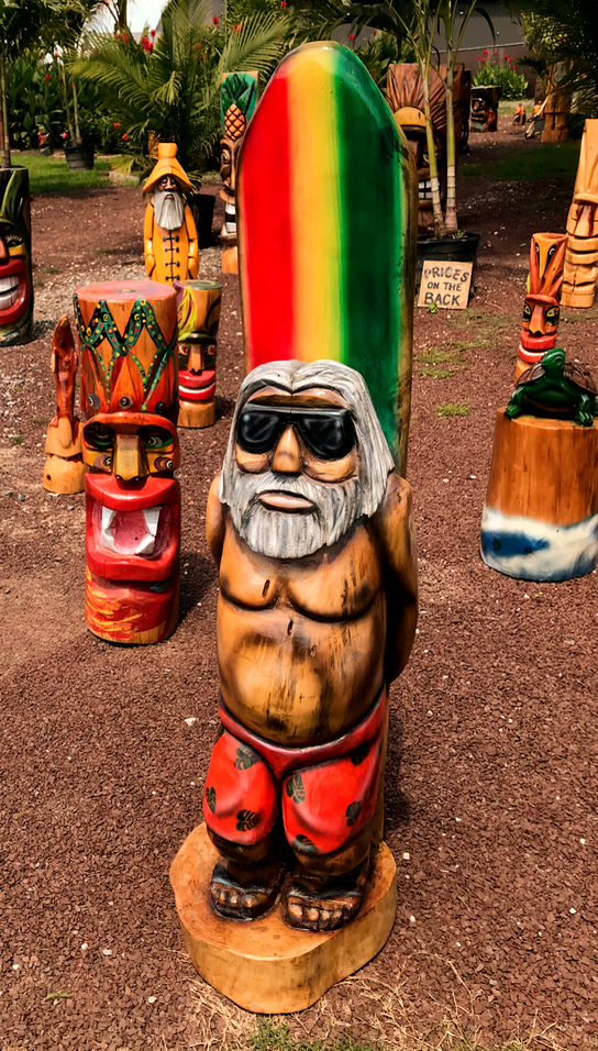 Tiki Murph white pine carved surfer dude with red, yellow and green surfboard.