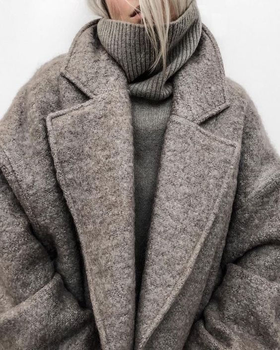 Stylish person wearing a cozy grey textured coat and turtleneck sweater.