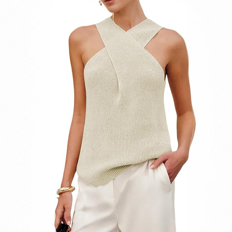 Fashionable woman models cream sleeveless criss-cross halter top and white pants.