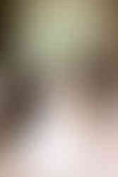 A bride leans over a counter standing beside her wedding cake