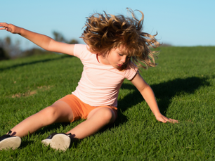 A clumsy child falling on the grass
