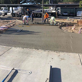 Construction workers leveling fresh concrete on a new driveway.