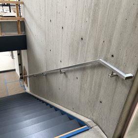 Modern metal handrail on a concrete wall by a staircase