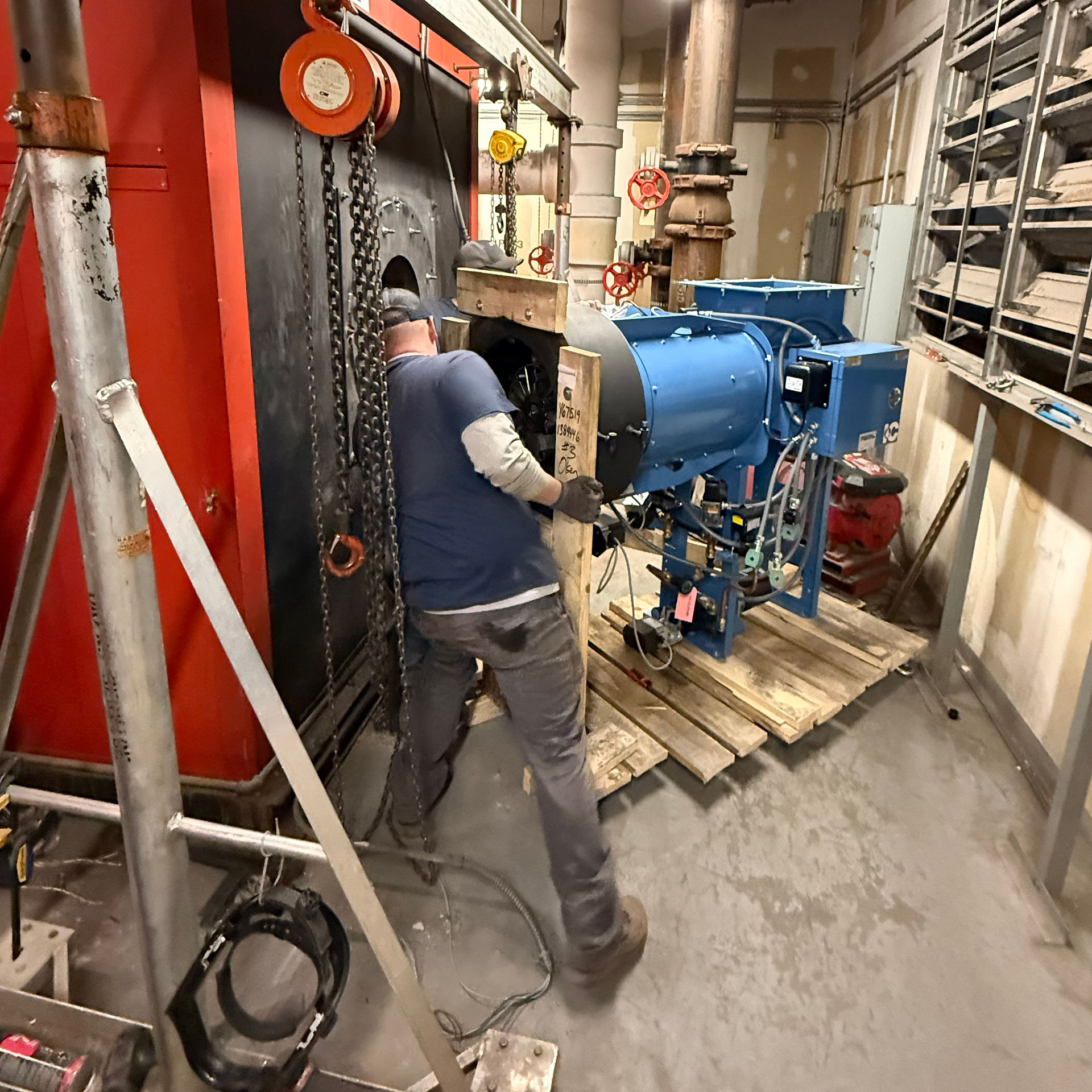 Technician aligning and securing the new Industrial Combustion burner onto the boiler housing during installation.