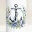 Miniaturbild: Weiße, maritime Kerze mit Anker-Motiv und Blumen - Detailansicht der Trauerkerze