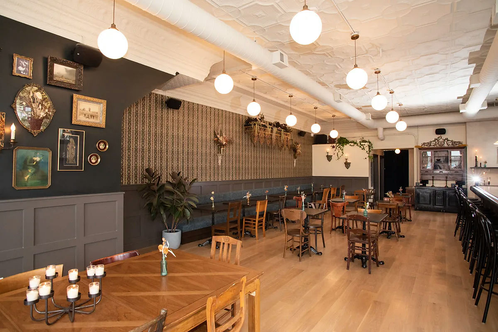 Cozy cafe interior with wooden tables and chairs, vintage decor, patterned walls, hanging lights, and a warm ambiance. Candles on tables.