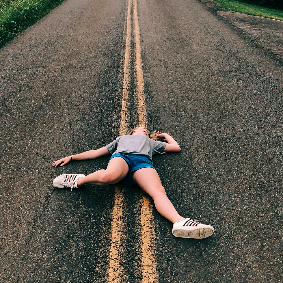 Exhausted young woman lies on road.
