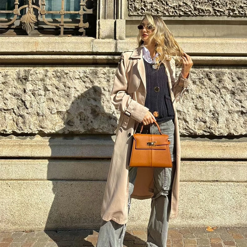 Thumbnail: “Woman in neutral outfit holding brown structured handbag on city street, elegant modern style with urban European aesthetic”