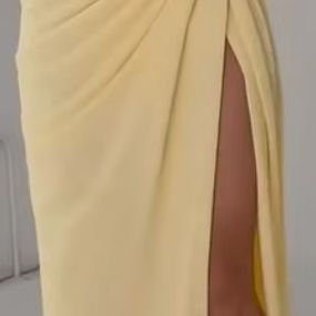 "Woman wearing a strapless yellow evening dress with a high slit, showcasing an elegant and sophisticated look."