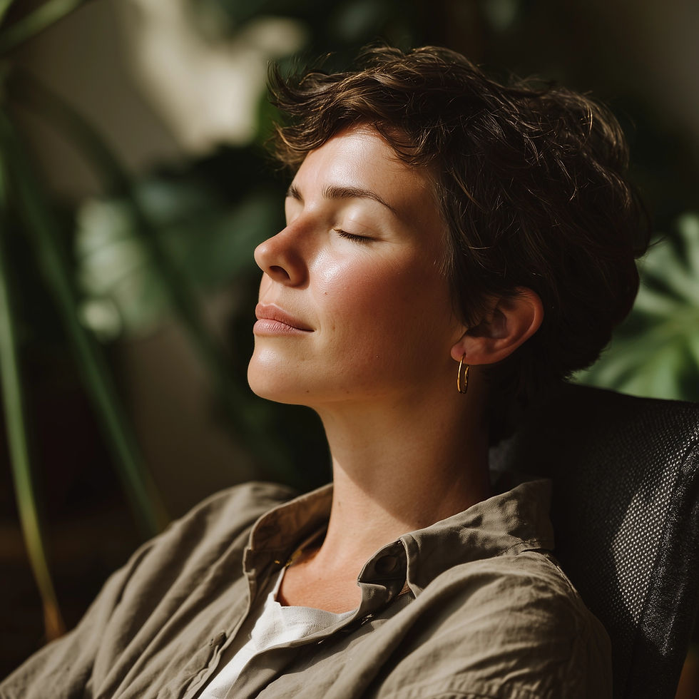 A person with short hair relaxes with eyes closed, wearing a gold earring and a beige shirt. Sunlight and green plants in the background.