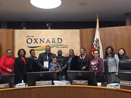 People standing and holding an award presented to the volunteer