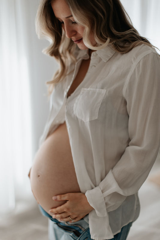 Close up of baby bump with soft natural light in Maryland studio | Baltimore maternity session