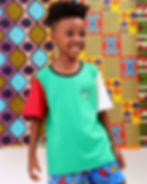 Criança negra com camiseta verde, ilustração pequena no frontal, uma manga vermelha e outra na cor off white.