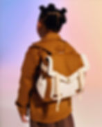 Menino negro com mochila infantil na cor caramelo e detalhes na cor de algodão cru.