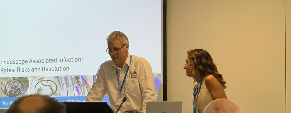 Doctor Herra and Malcolm presenting an analysis of recent hospital-acquired infection outbreaks linked to endoscope use. The discussion highlights probable causes of contamination and explains why manual cleaning of flexible endoscopes remains a critical vulnerability in infection control within healthcare facilities.