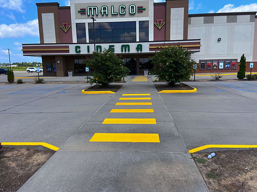 Movie theater parking lot after having curbs, crosswalks and light pole bases painted safety yellow.