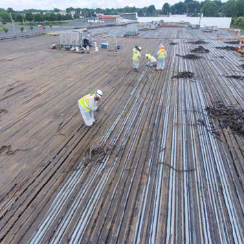 RCI workers wearing safety equipment while removing asbestos containing roofing materials