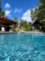 Light blue water rippling in a heated salt water pool surrounded by gardens at pool cabanas at The black Swamp Bunkhouse.