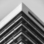 Zu sehen ist die Dachspitze eines Hochhaus (Landgericht Innsbruck). Das Bild ist so aufgenommen, dass die Lauflinien ein sauberes in der Mitte zulaufendes "V" bildet. In der Mitte des Bildes liegt das Logo von CONIURIS (der "CON" Paragraph).