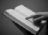 Hand zeigt auf Text in einem aufgeschlagenen Buch.