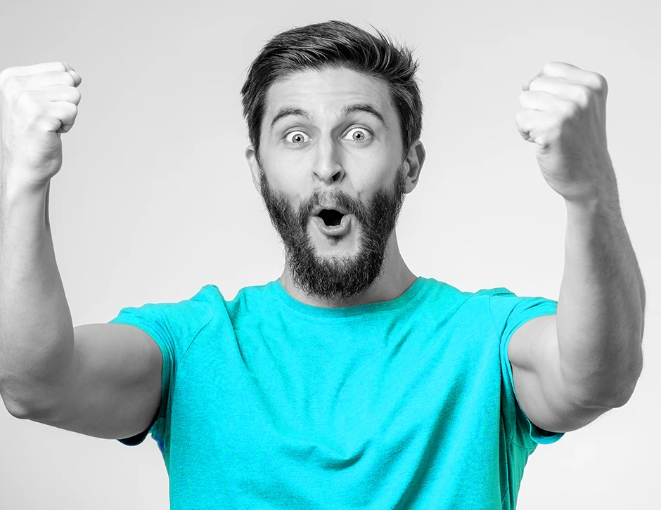 An excited man with a blue shirt raising his arms in celebration