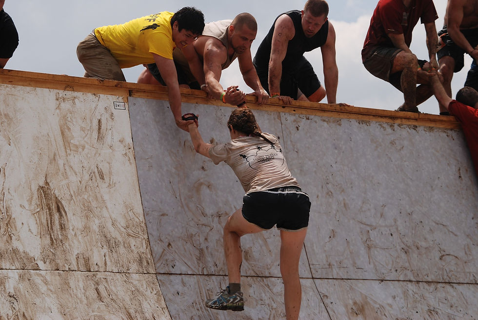 Woman being helped as she challenges herself to climb
