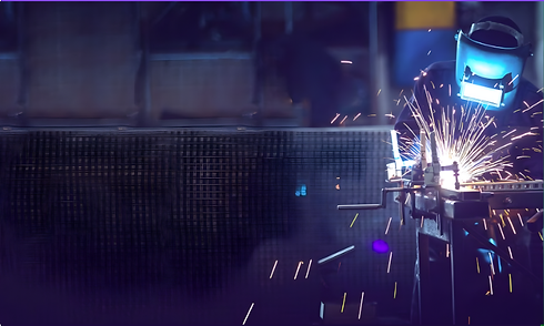 Welder working with sparks in a factory, creating structural metal HOME