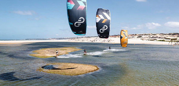 trois personnes pratiquant le kitesurf sur un plan d'eau sécurisé