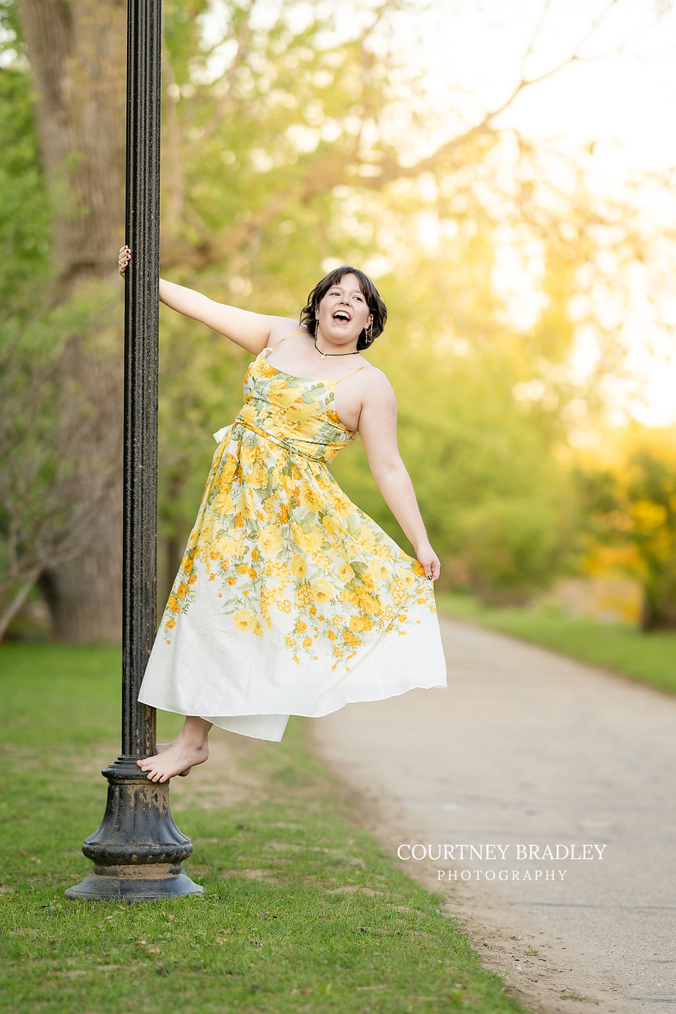 senior picture in grand ledge at island park swinging on light pole signing