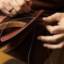 Hands stitching leather by hand at the Hermès atelier, photographed by Giampaolo Vimercati.