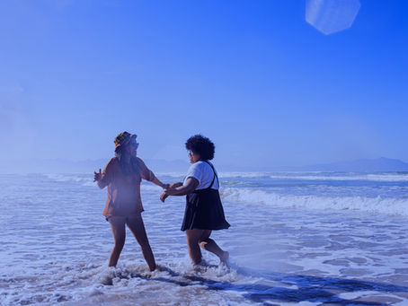 two women caught in a small wave on a beach