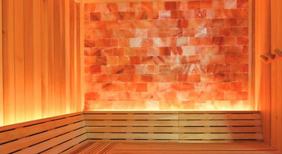 Sauna interior with glowing Himalayan salt wall and wooden benches.
