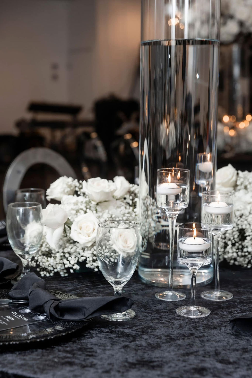 Close-up of guest table with white rose and baby’s breath centerpiece and silver decor at the Melanated Christmas Ball