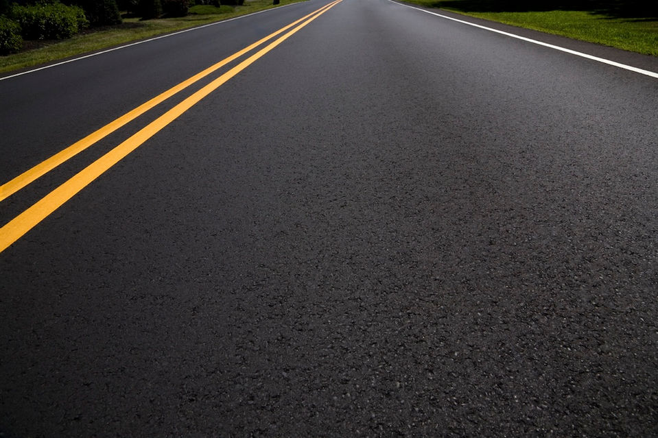 Asphalt road with double yellow lines, leading to the horizon