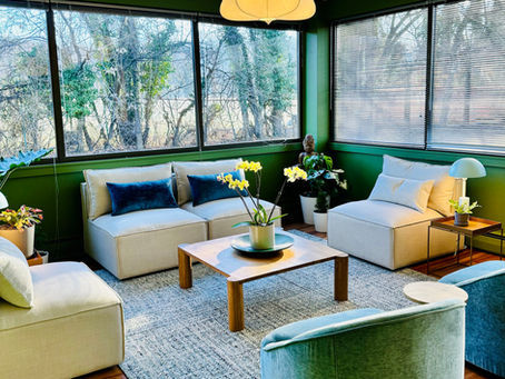Bright modern lounge with green walls, cream sofas, blue chairs, orchids, large windows, and warm pendant lights. Very Well Baltimore MD