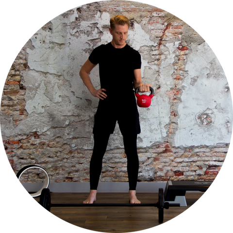 Man training with kettlebell against rural wall