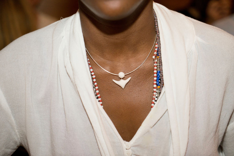 a woman wearing a white necklace with a shark tooth pendant