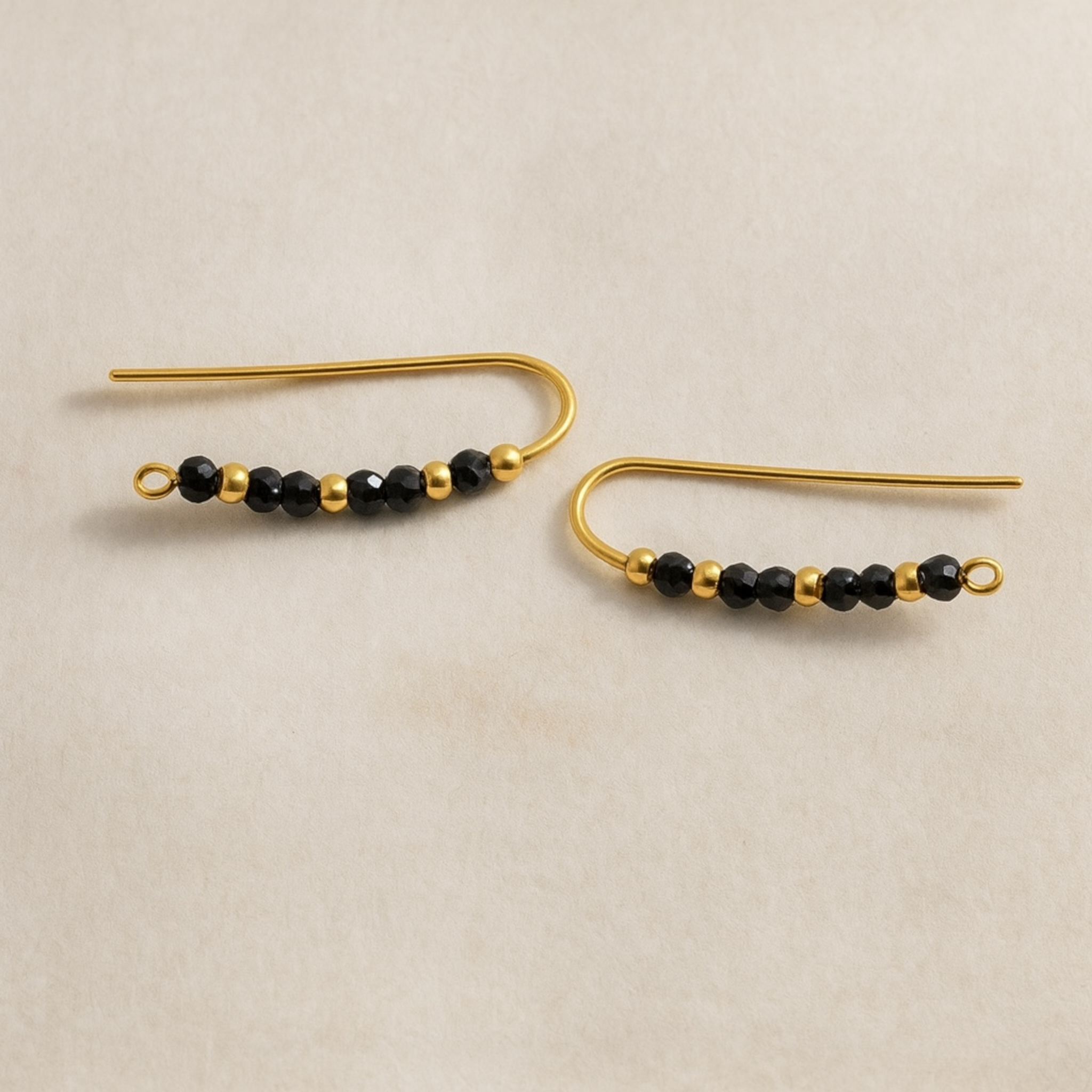 Boucles d’oreilles Climbers en Gold filled et Spinelle noire sur fond blanc