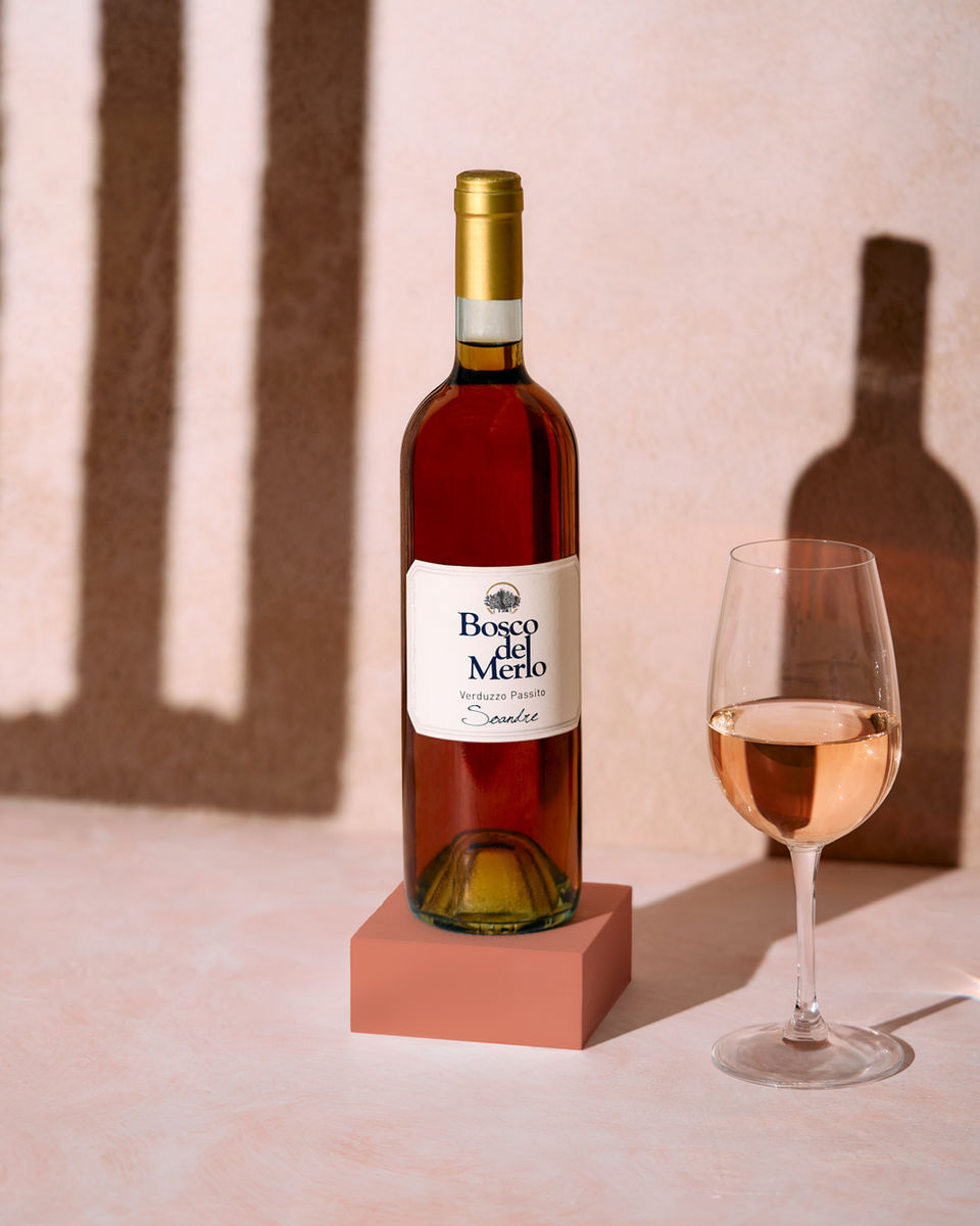 VINO BOSCO DEL MERLO (3139 ) con bicchiere vicino. La luce entra dalla finestra e crea delle ombre dure