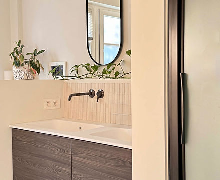 Miroir aux formes courbes et luminaire design pour un coin vasque élégant.