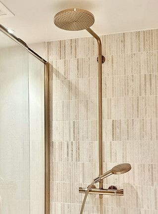 Revêtement de salle de bain en zellige artisanal et robinetterie encastrée minimaliste.