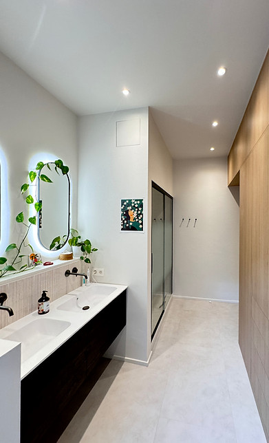 Aménagement d'un meuble vasque minimaliste avec miroir organique et robinetterie encastrée en laiton.