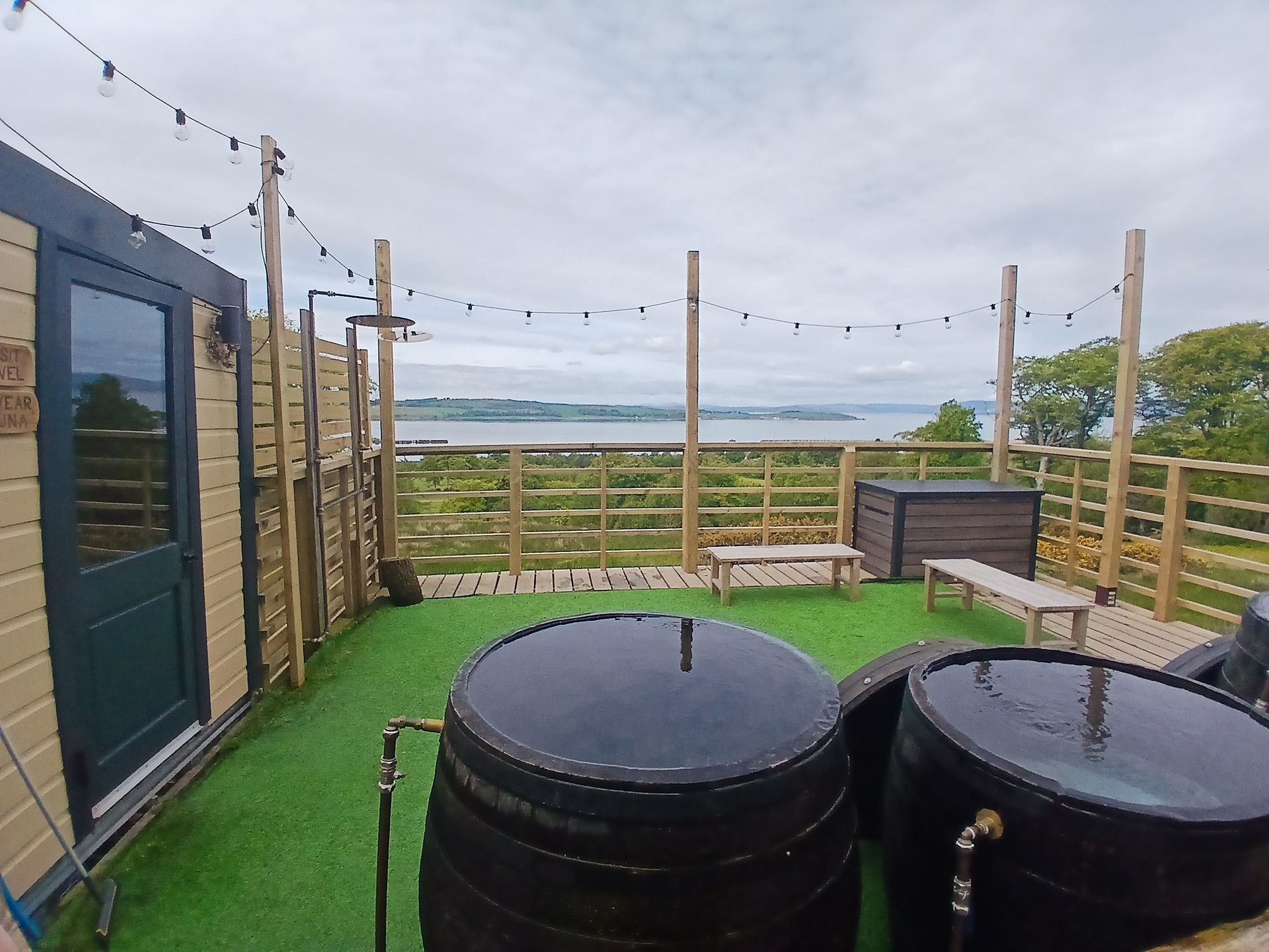 Two barrels filled with water outside a sauna, views out to the sea